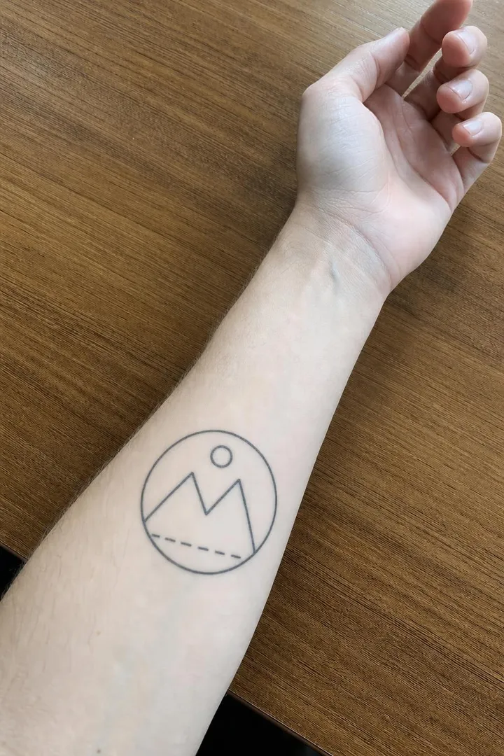 The same drawing tattooed on the forearm, healed into the skin.