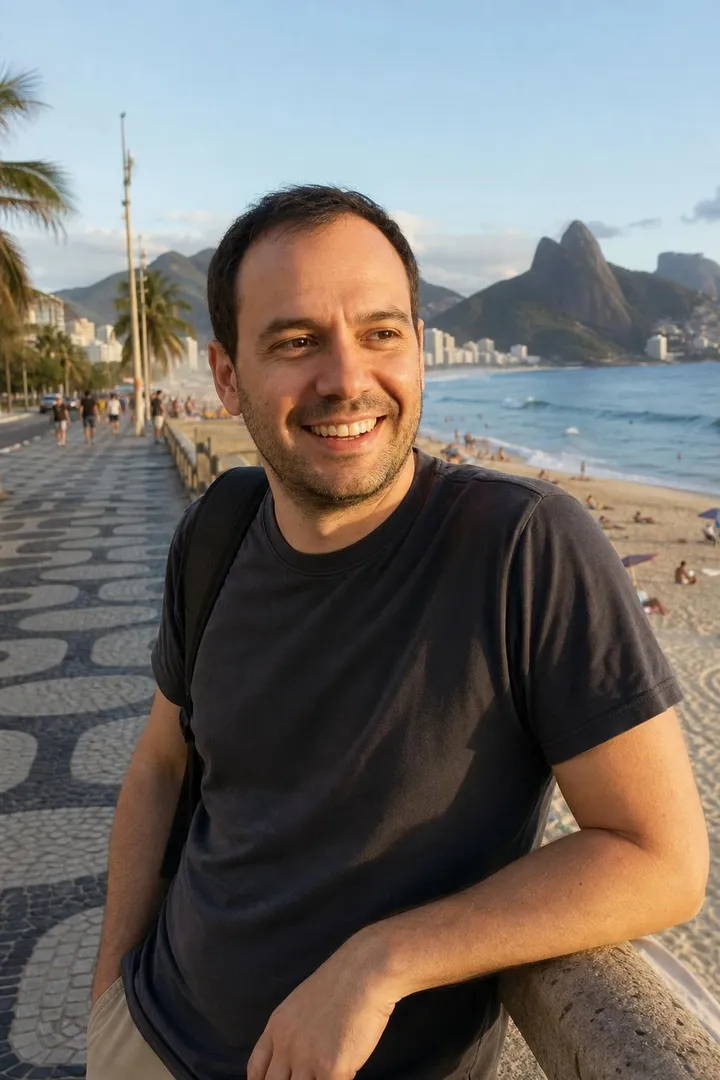 The same man laughing on the wave-patterned Ipanema promenade, beach and mountains behind.